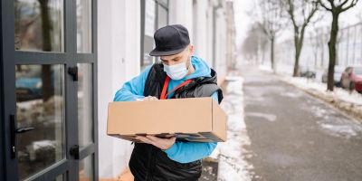 image of delivery person trying to deliver a box but is confused and looking at label on box trying to find the right address